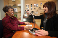 One woman showing another woman a desktop lamp